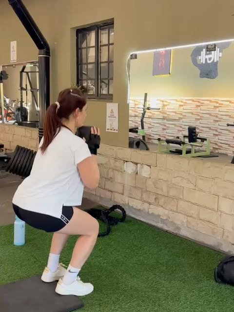 Área funcional de Gym Brasil, con césped sintético, espejo, kettlebells y colchonetas