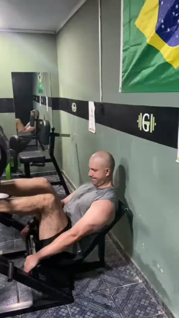Sala con pared verde, bandera de Brasil y prensa de piernas